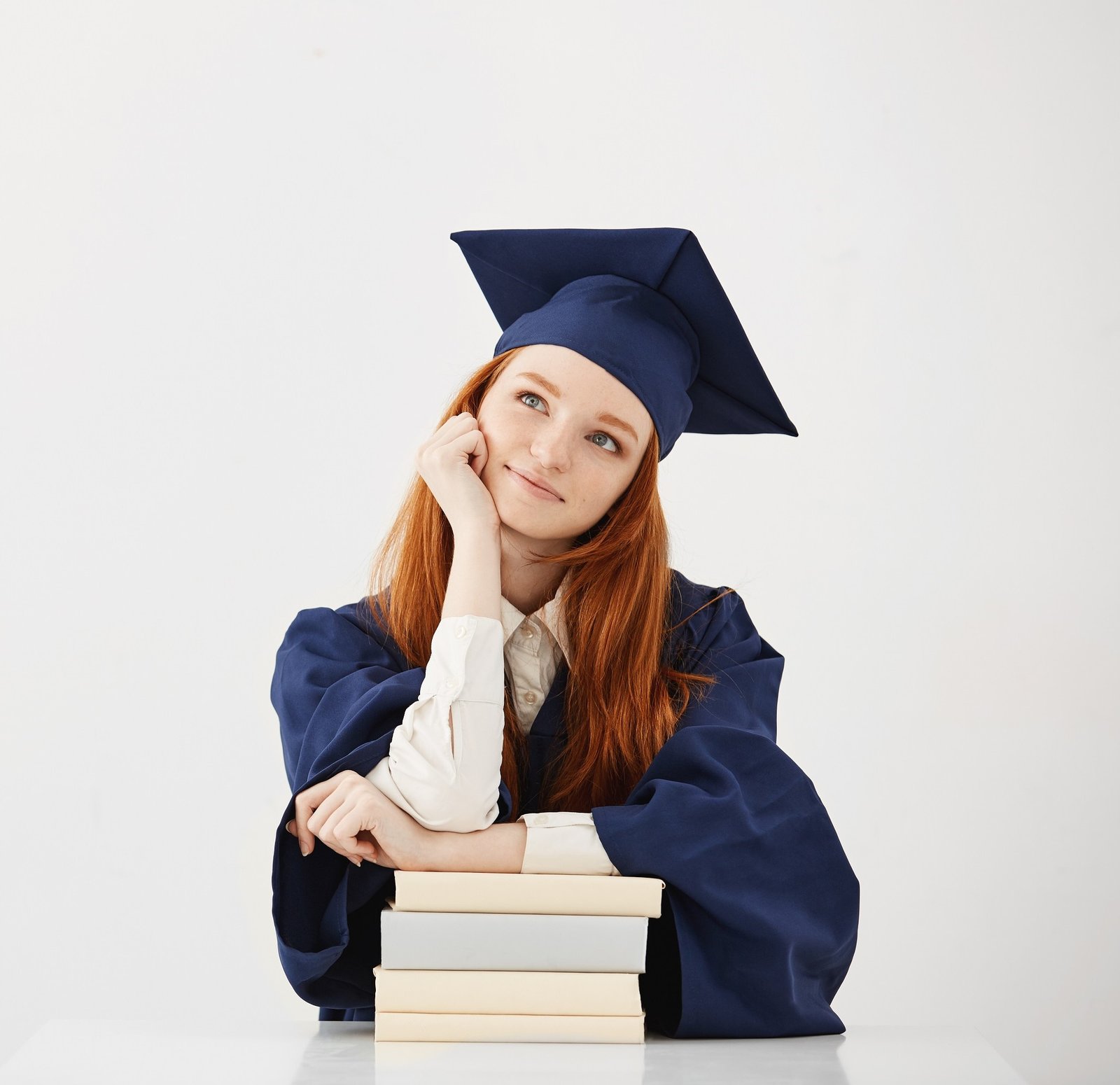 Dreamy graduate girl smiling thinking sitting with books. Copy space. kursus bahasa inggris online